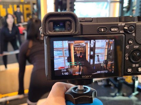 열린의 문성준 PD가 트레이너 모델을 촬영하고 있다. 운동 영상 콘텐츠를 직접 촬영 및 편집해 회원에게 제공하며, 영상은 헬스클럽내 TV모니터와 모바일을 통해 시청할 수 있다