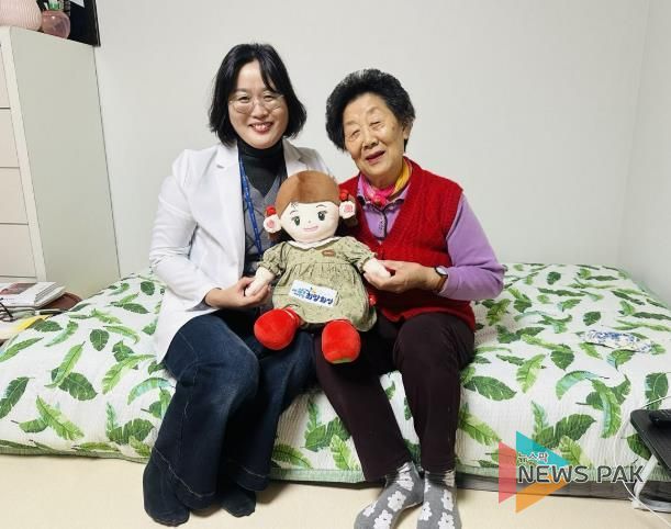 화성시동탄보건소 관계자와 독거 어르신이 AI 돌봄로봇 ‘효돌이’를 함께 들고 환하게 웃고 있다